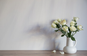 white roses in white jug on background gray wall