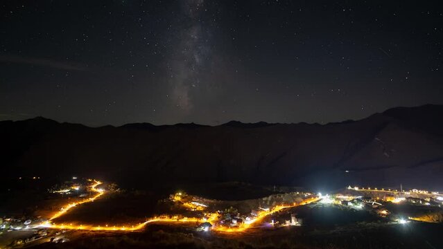 Milky Way and starry sky over a mountain valley with a busy highway and lights and trees, 4k, timelapse
