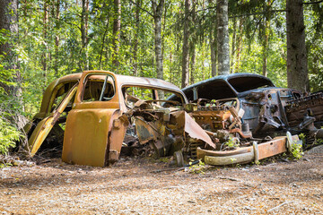 Old abandoned car wreck hidden in a forest, famous dark tourism destination in Sweden