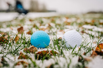 Two golf balls stand in the snow to see the difference as you can see. White and blue. Golf game in...