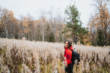 Naklejka na ściany i meble Girl traveling alone with backpack in the forest, hiking in autumn esu, young beautiful woman trekking in nature.