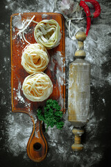 Raw pasta in composition with kitchen accessories in the kitchen on the table.