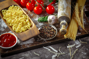 Raw pasta in composition with kitchen accessories in the kitchen on the table.
