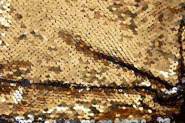 Gold round shaped sequins attached to the fabric. Background texture