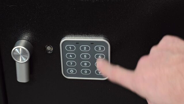 A man places a loaded revolver and a portable hard disk containing important data and information into his home safe. This scene illustrates the responsible storage of weapons 