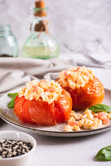 Baked tomato halves filled with scrambled egg and basil on a plate on the table vertical view