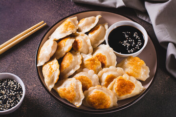 Crispy fried dumplings with soy sauce and sesame seeds on a plate on the table