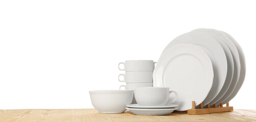 Set of different clean dishware on wooden table against white background