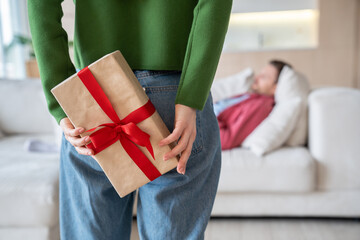 Gift box with red ribbon for holiday. Romantic surprise woman holding present behind back going to...