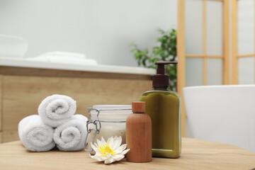 Fototapeta na wymiar Different spa products and beautiful flower on wooden table in bathroom