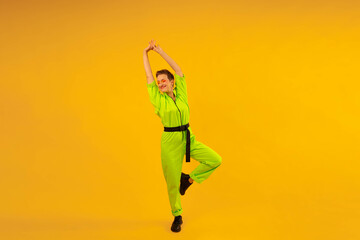 Fototapeta na wymiar Full length body size photo of happy woman wear modern green overalls on bright yellow color background. Cheerful and energetic middle age female with colored make up having fun near copy space