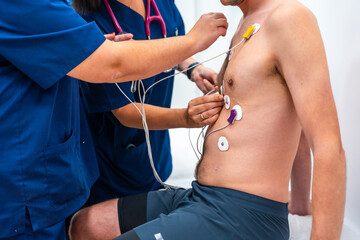 Cropped close-up photo of two cardiologists placing electrodes to a patient to perform a...