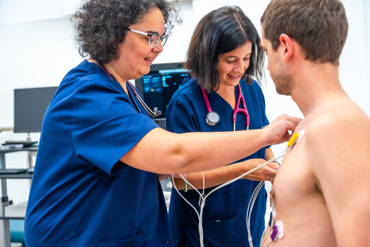 Cardiologist placing electrodes on a patient for a stress test
