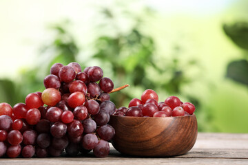 Delicious fresh red grapes on wooden table against blurred background. Space for text