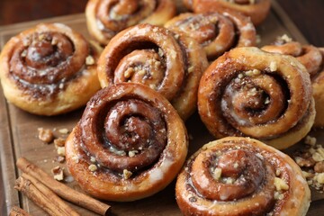 Tasty cinnamon rolls, sticks and nuts on table, closeup