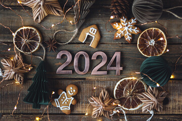 2024 Christmas or New Year composition. Holidays card on wooden background with gingerbread...