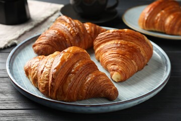 Delicious fresh croissants on black wooden table, closeup