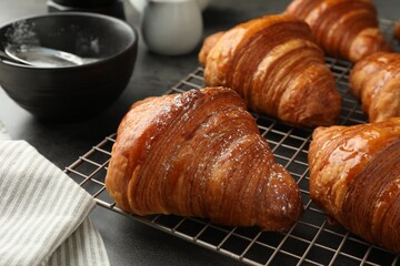 Delicious fresh croissants with powdered sugar on grey table, closeup