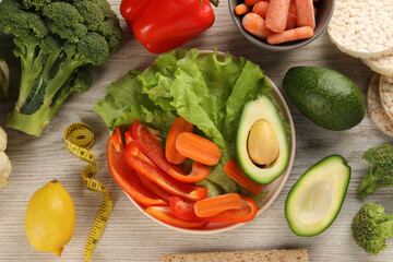Healthy diet. Fresh vegetables and measuring tape on light wooden table, flat lay
