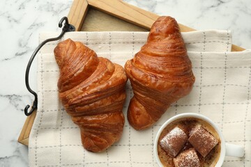 Tasty croissants served with cup of hot drink on white marble table, top view