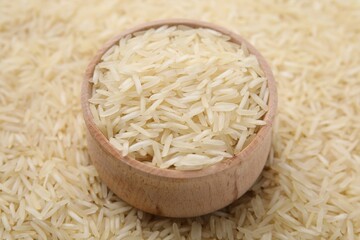 Bowl and raw rice as background, closeup