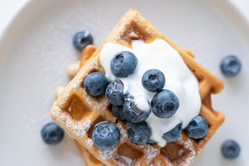 Belgian waffles with blueberries and honey on a white background. Serving breakfast with homemade cakes.