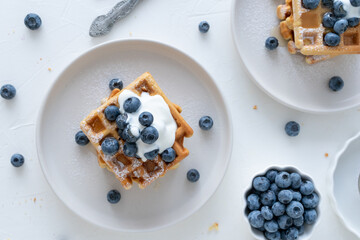 Belgian waffles with blueberries and honey on a white background. Serving breakfast with homemade cakes.