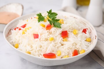 Bowl of delicious rice with vegetables and parsley on light table, closeup