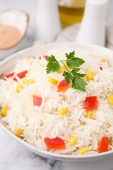 Bowl of delicious rice with vegetables and parsley on table, closeup