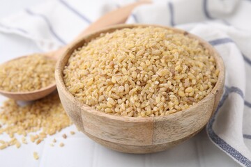Raw bulgur in bowl on table, closeup