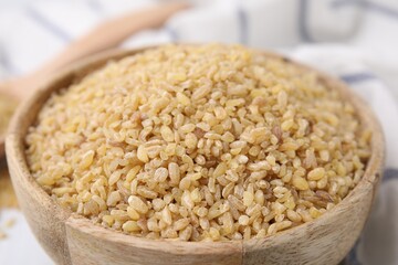 Raw bulgur in bowl on table, closeup