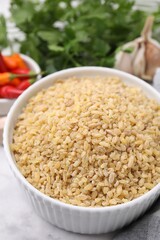 Raw bulgur in bowl on table, closeup