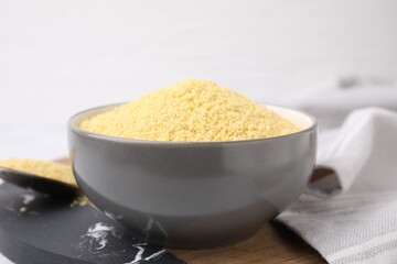 Raw couscous in bowl on table, closeup