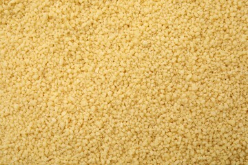 Uncooked organic couscous as background, top view