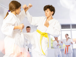 Children pupils train to perform defensive karate installations and attacking actions for combat techniques classes. Teenagers prepare for competition, with guidance of coach repeat combat skills