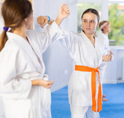 Children students athletes at Academy of martial Arts practice karate and fight opponents in pairs. Obtaining black belt, advanced training, highest dan of martial arts. Wrestling as an art