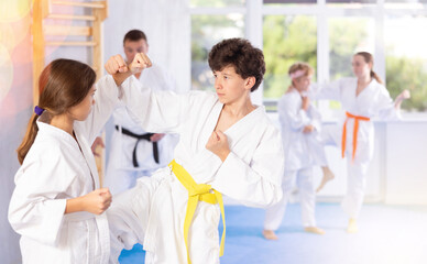 Fototapeta na wymiar Boy and girl karatekas train karate in group in studio