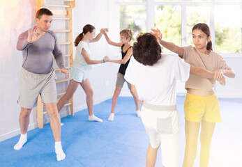 Obraz premium Boy and girl practicing self-defense techniques in group at gym