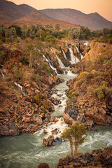 Epupa Falls, Kunene Region, Namibia, in warm, golden light. Epupa Falls is a series of large waterfalls formed by the Kunene River on the border of Angola and Namibia.