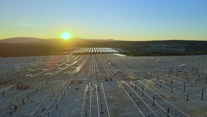 Solar farm construction site, large field for solar panels, aerial view sunset