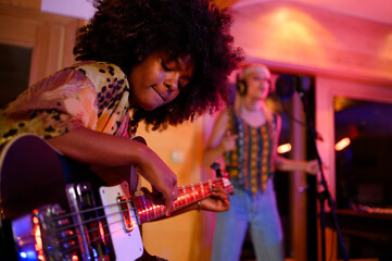 A multiracial bass player improvising and jamming in a music studio, recording session.
