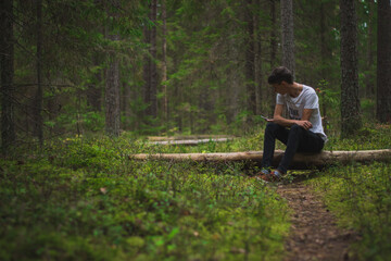 A person sitting among trees in a lush green forest.