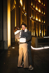 loving couple in winter clothes walks the city in the evening, happy young people in cold weather.