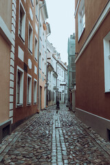 Fototapeta na wymiar Empty street with cobble stone floor in the ancient neighbourhood in Riga, Latvia on a grey autumn day