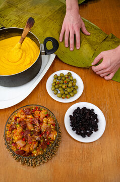 Manos preparando las hojas de pl&aacute;tanos para armar las hallacas, plato tradicional navide&ntilde;o de Venezuela, similar a los tamales. Elaborado con masa de ma&iacute;z, guiso de carne y pollo, aceitunas y pasas.  