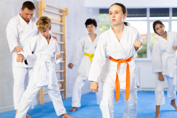 At single combat arts class, children learn basic techniques and positions. Teacher corrects pose posture position of body, hands, legs during karate classes.