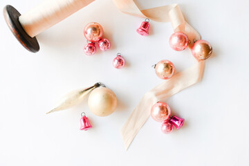 A pink spool of thread lies on a white background and pink objects around