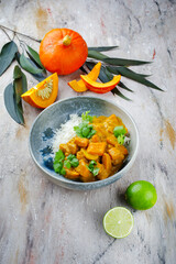 Traditional Indian vegetarian curry stew with sweet potatoes, pumpkin and rice served as close-up in in a Nordic design plate