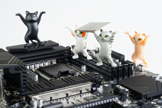 Cute toy kittens mount a computer processor into a socket on the motherboard. Study of computer technologies. Assembling, overclocking and upgrading modern computer. Photo. Selective focus