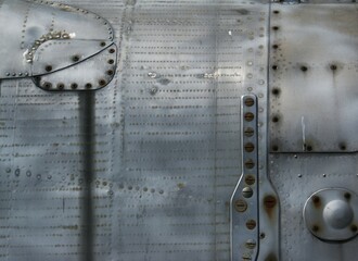 Metallic background with screws and rivets. A fragment of the fuselage of an old fighter.